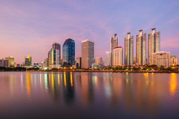 Scenic view of a lake at the Benjakiti (Benjakitti) Park and skyscrapers in Bangkok, Thailand, at sunset.