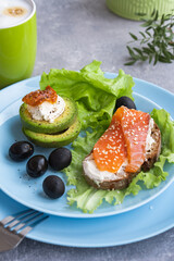 Healthy breakfast. Sandwich with smoked salmon, avocado cheese on lettuce salad leaves and coffee