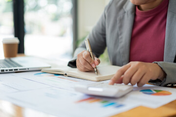 Business analyst concept the accountant using calculator to check the correctness of the data in the laptop