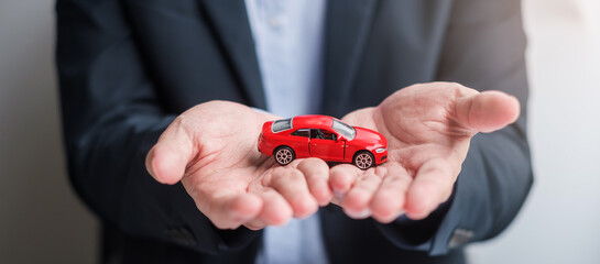 Businessman hand holding red car toy with vehicle keyless, pen and contract document. buy and sale,...