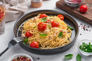 Fetapasta, pasta with cherry tomatoes, feta and basil on a gray background.