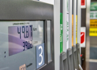 Gas prices at a petrol pump in a petrol station. Close up on fuel nozzle in oil dispenser with...
