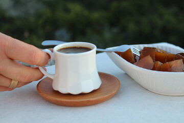 A woman drinking coffee and eating pumpkin dessert known as “kabak tatlisi” or “kirecte kabak” in Turkey. Hatay cuisine. 