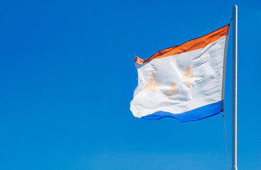 New Orleans flag on a blue sky background.
