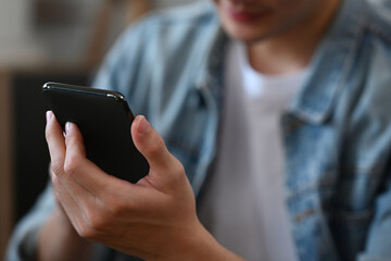 Close up image of male typing text message on smartphone.