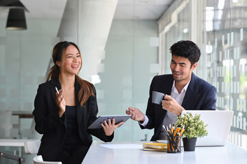 Happy business colleagues sitting together in modern office and discussing project ideas.