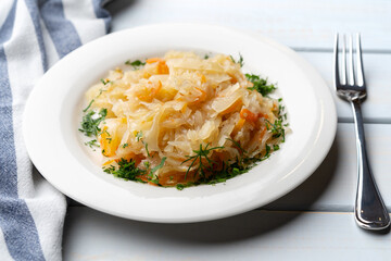 Plate of tasty stewed cabbage on wooden table