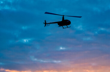 Helicopter silhouette with sunset sky on the background.