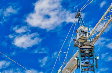 New construction site with cranes on blue sky background. Steel frame structure, structural steel...