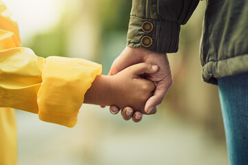 Always hold hands when crossing the road. Closeup shot of an unrecognizable little boy and his mother holding hands in the rain outside. © Arnéll Koegelenberg/peopleimages.com
