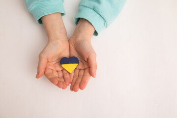 High angle view of child hands holding ukraine flag painted heart