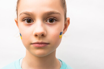 face of a frightened girl, a painted heart on the cheek in yellow-blue colors of the Ukrainian flag.