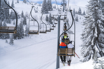 Skiers climb on a two-seater cable car to the top of the mountain