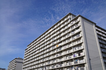 Fototapeta premium そびえ立つ昭和に建てられた古い団地、ファミリーマンション、青空に伸びる古いマンション、