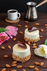 Two cupcakes with chocolate white coffee cup almond and tulips on wooden table. Selective focus