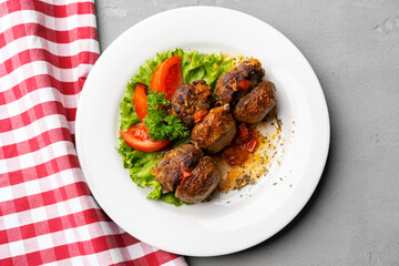 Cooked meat with fresh vegetable salad on a white plate