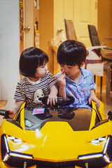 Brother and sister playing together in yellow toy car at home. Children playing in the car. Two brothers play together in a toy car. Family Concept.
