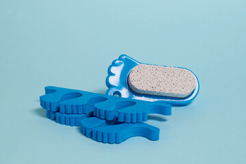 Pedicure accessories. Finger separators and pumice stone on a blue background