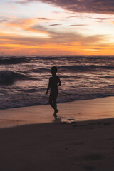 Naklejka premium Child boy on the ocean at sunset, happy childhood, unity with nature, harmony.