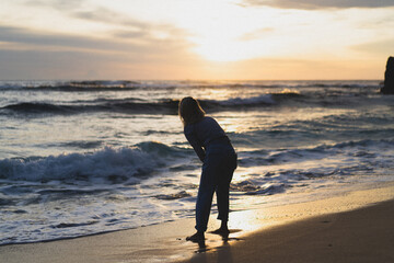 Young woman by the ocean at sunset.