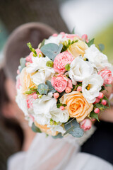 wedding bouquet large in the hands of the bride and groom. dercore of roses