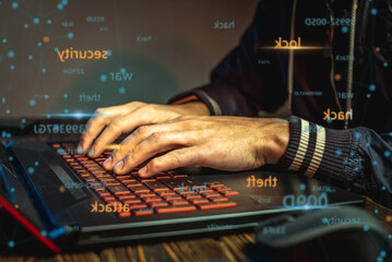 Hands in type on a laptop keyboard in close-up. The concept of cybercrime fraud and identity theft