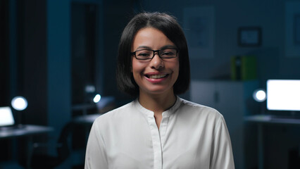 Fototapeta premium Medium shot of smiling African-American businesswoman looking at camera in office