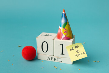 April 1st. Image of april 1 wooden calendar and festive decor on the blue background. April Fool's Day - obrazy, fototapety, plakaty