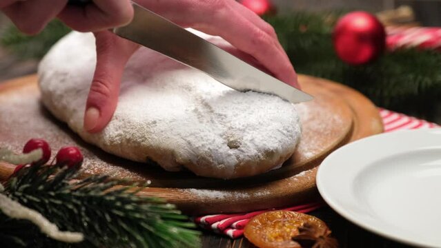 Woman slicing Traditional Christmas stollen cake with marzipan and dried fruit