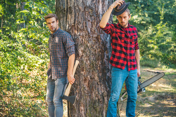 Man with axe in forest. Lumberjack woodcutter in a plaid shirt. Lumberjack brutal bearded man in...