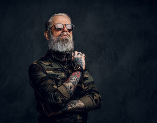 Stylish grandfather with sunglasses and crossed arms against dark background