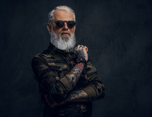 Stylish grandfather with sunglasses and crossed arms against dark background