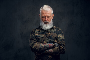 Elderly man dressed in camouflage suit against dark background