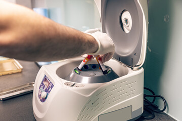 Scientist putting blood samples into centrifuge.