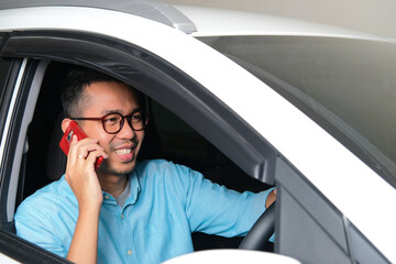 Adult Asian man talking on the phone while driving his car