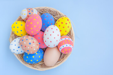 Colorful eggs in a basket on blue background	