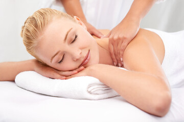 Fototapeta na wymiar This masseuse has miracle hands.... A beautiful young woman enjoying a massage at a spa.