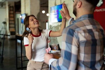 Young colleagues taking break after work. Happy young businessman and businesswoman playing darts...