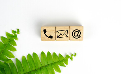 Wooden cube with symbols phone icon, email, address. Website page. Contact us or email marketing...