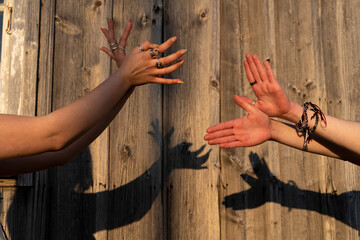 Zwei junge Frauen projizieren Friedenstauben an eine Holzwand mit ihren Händen. 