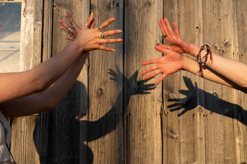 Zwei junge Frauen projizieren Friedenstauben an eine Holzwand mit ihren Händen. 