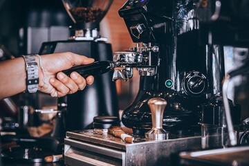 Barista making coffee with coffee machine in cafe.