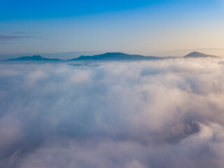Flight over fog in Ukrainian Carpathians in summer. Mountains on the horizon. Aerial drone view.