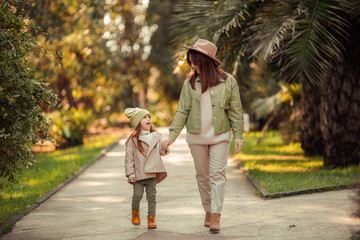 Fototapeta premium red-haired mother and daughter are walking in the park. family leisure in the city