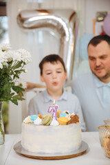 Father with son celebrate children's birthday party at home. Child is 7 years old and blows the candles on the cake. Single father with his son 