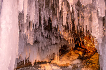 Icicles in cave on Baikal lake at sunset