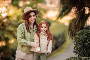 Fototapeta premium red-haired mother and daughter are walking in the park. family leisure in the city