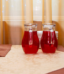 Two glass jugs of cranberry juice on the table
