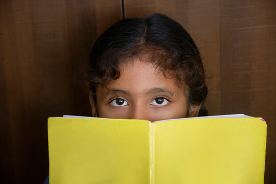 school girl covered her face with book