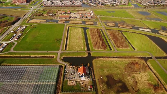Aerial Tilt Up View Over Agricultural Greenhouses In Fields To Reveal Rotterdam Skyline In Distance